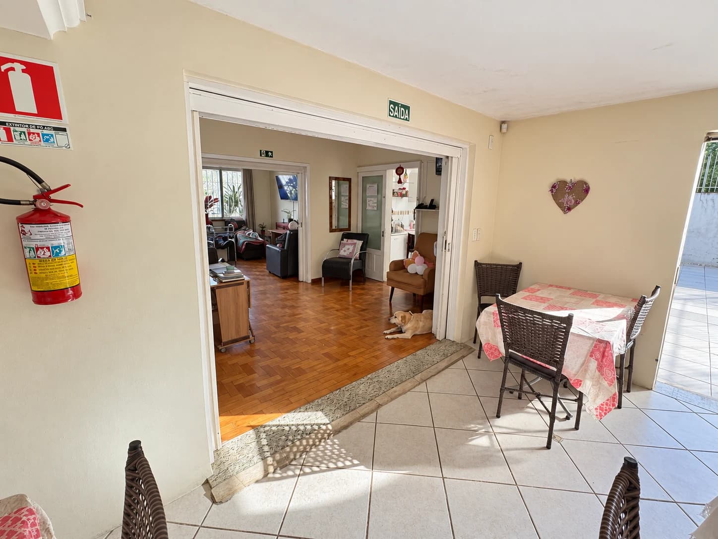 Passagem da sala de refeições para a sala de estar, com poltronas e piso de madeira